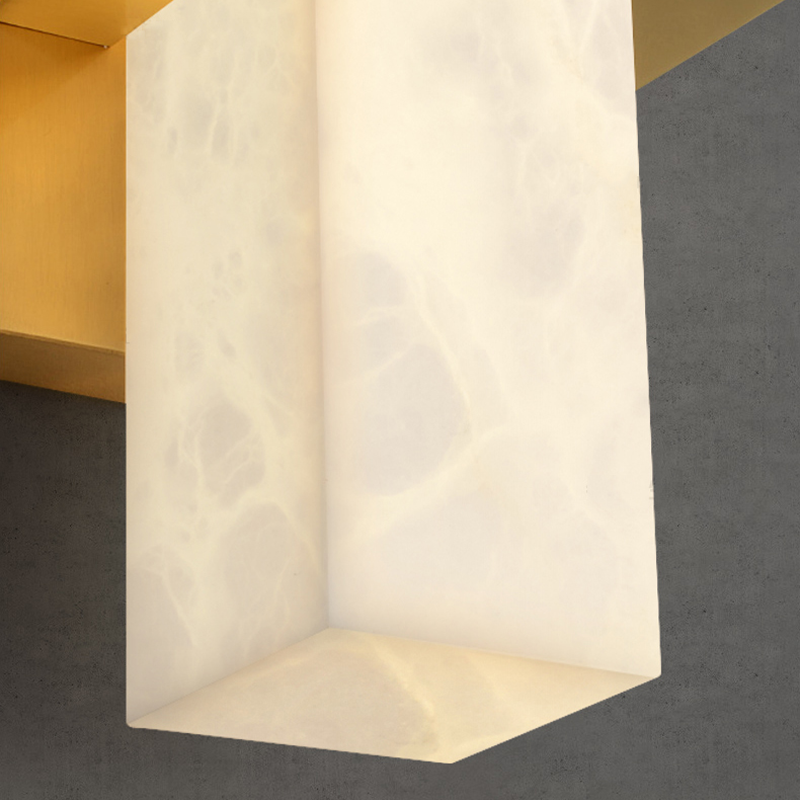 Close-up of the square marble shade and golden base of the wall lamp.