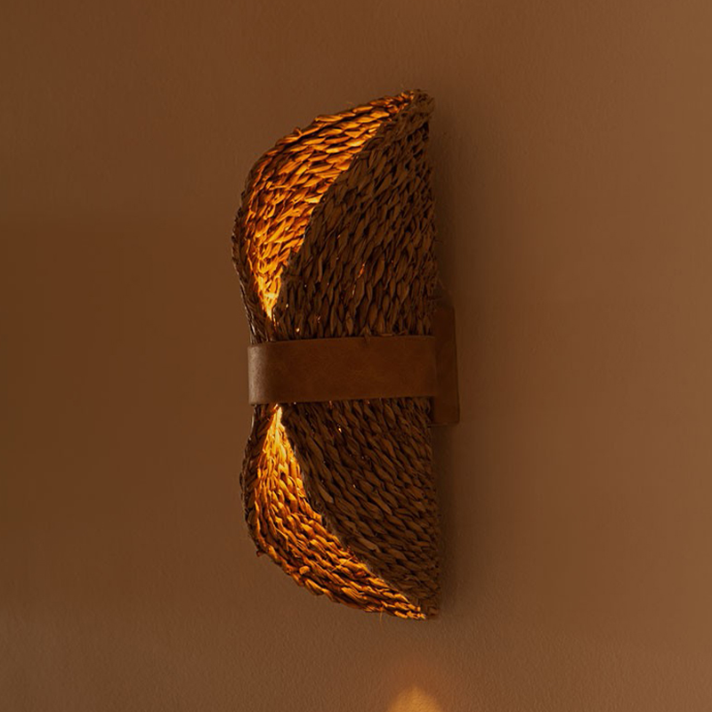The rattan wall lamp illuminating a cozy bedroom corner, enhancing the boho decor theme.