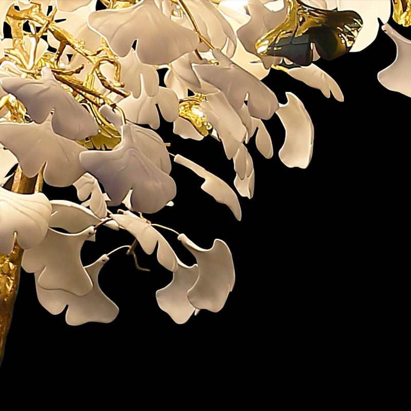 Ginkgo tree floor lamp glowing warmly in a stylish living room corner.