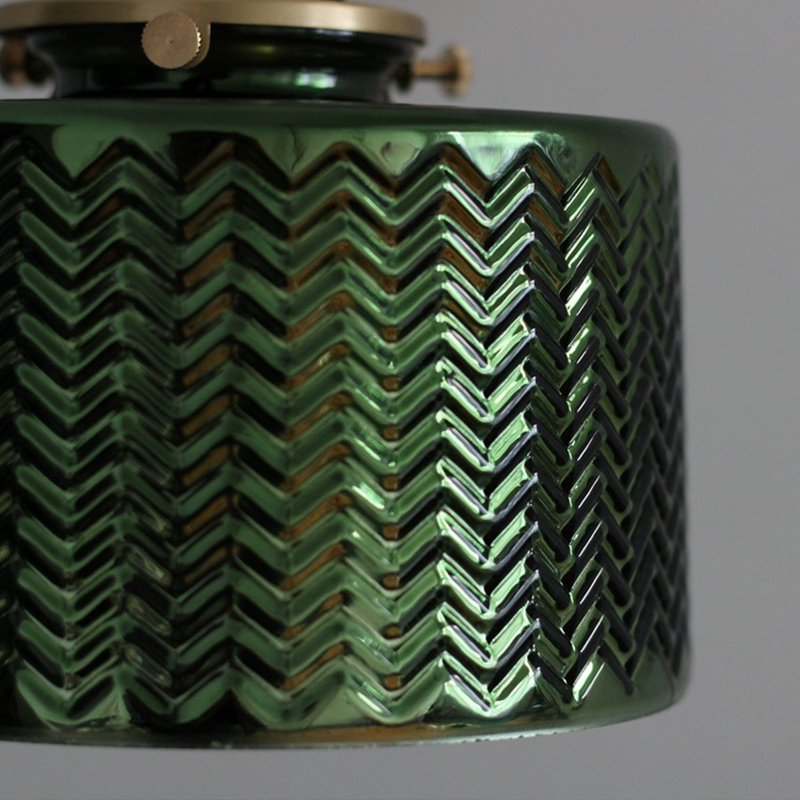 Elegant green glass wall sconce installed in a modern living room, providing warm ambient lighting.