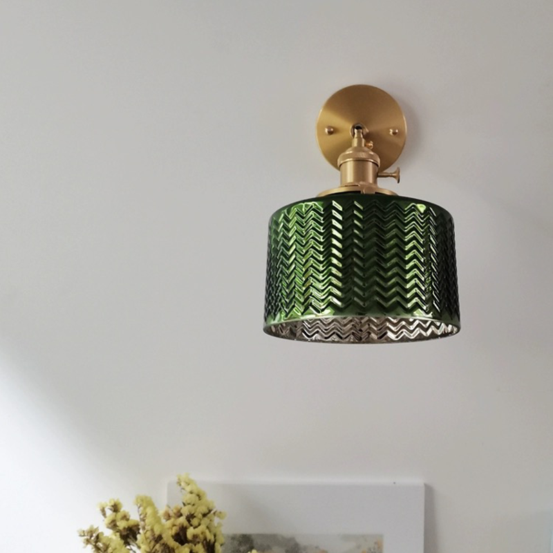 Elegant green glass wall sconce installed in a modern living room, providing warm ambient lighting.