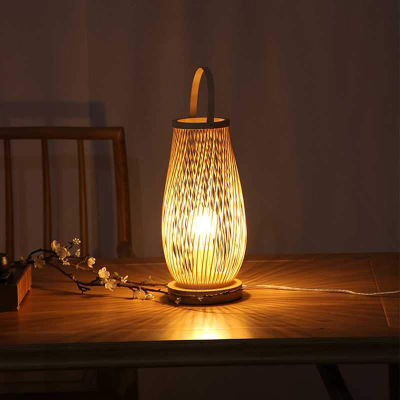 Angled view of the handmade bamboo lamp glowing warmly on a wood nightstand