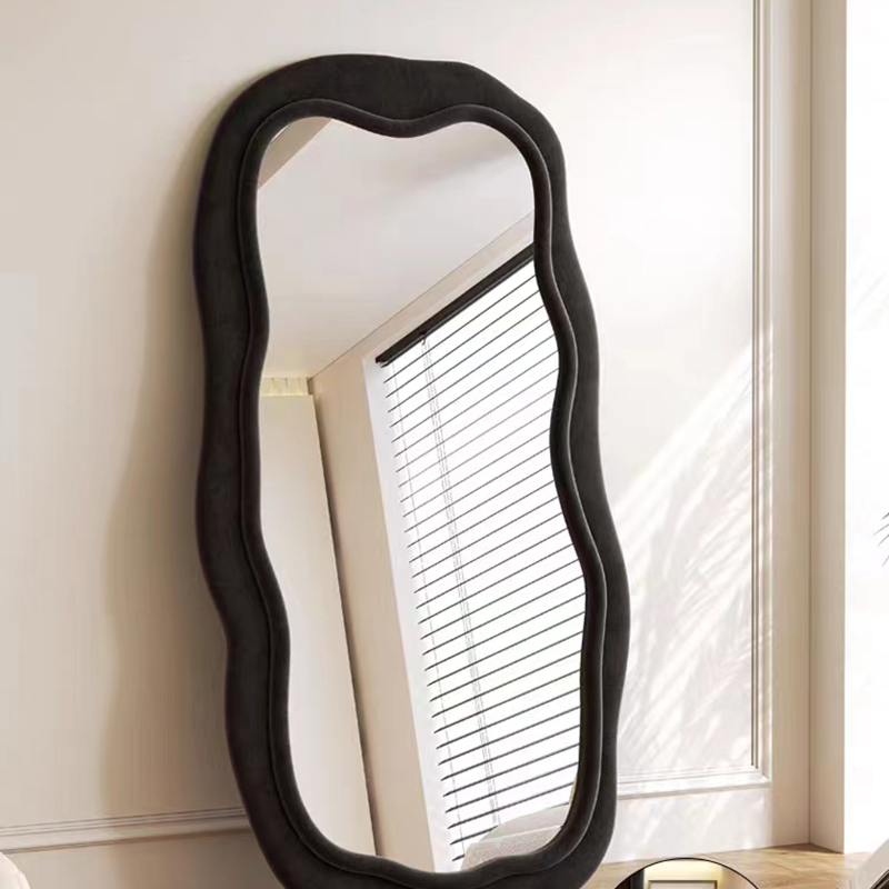 Wavy black full-length mirror positioned in a spacious bedroom highlighting its size and elegance.