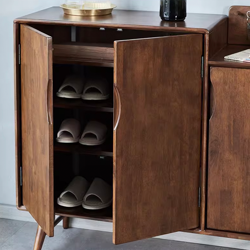 Side angle of rubber wood shoe cabinet with double doors placed in a modern entryway with boots and accessories