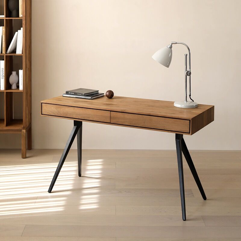 Close-up of the smooth teakwood surface and black iron legs of the desk.
