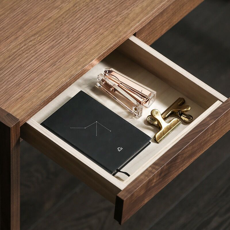 Close-up of the built-in pencil box and hidden cable management shelf of the writing desk.