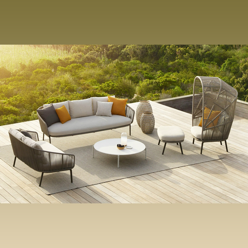 Luxury handwoven cocoon chair with a footstool in a garden setting.