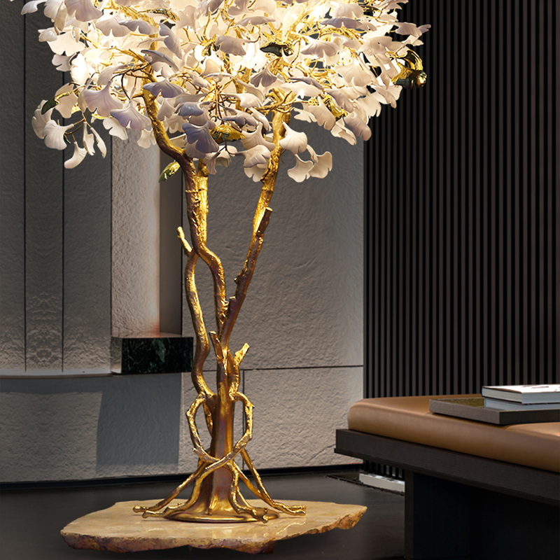 Ginkgo tree floor lamp glowing warmly in a stylish living room corner.