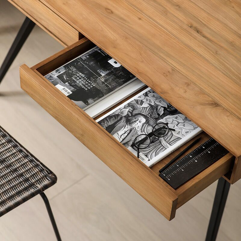 Close-up of the smooth teakwood surface and black iron legs of the desk.