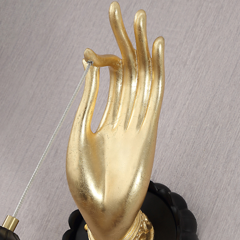 Buddha hand wall lamp displayed in a cozy bedroom setting.