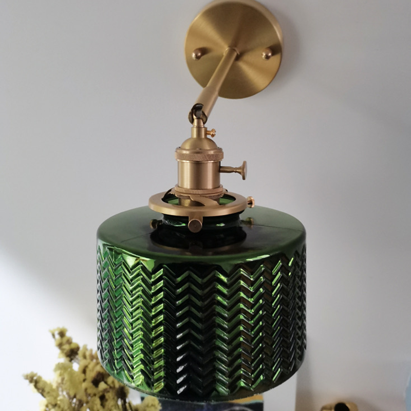 Close-up of the elegant green glass wall lamp showcasing its ripple design and brass details.