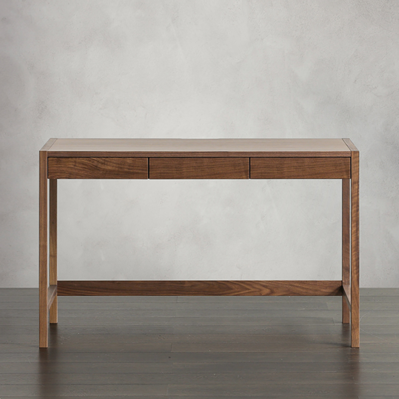 Side angle of the walnut writing desk, highlighting the three drawers and clean lines.