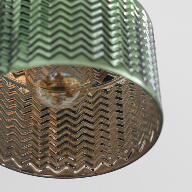 Close-up of the elegant green glass wall lamp showcasing its ripple design and brass details.