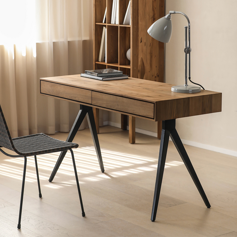 Close-up of the smooth teakwood surface and black iron legs of the desk.