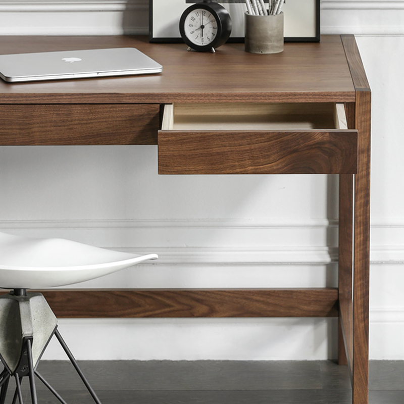 Side angle of the walnut writing desk, highlighting the three drawers and clean lines.