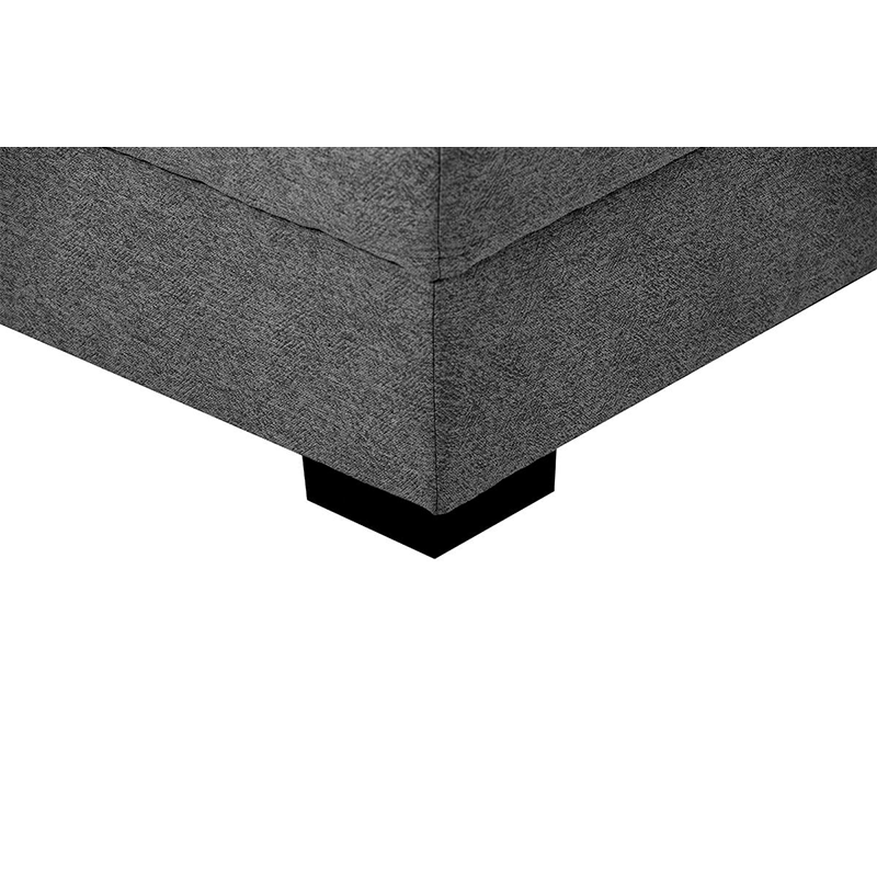 Dark grey tufted sectional sofa with matching ottoman in a contemporary living room.