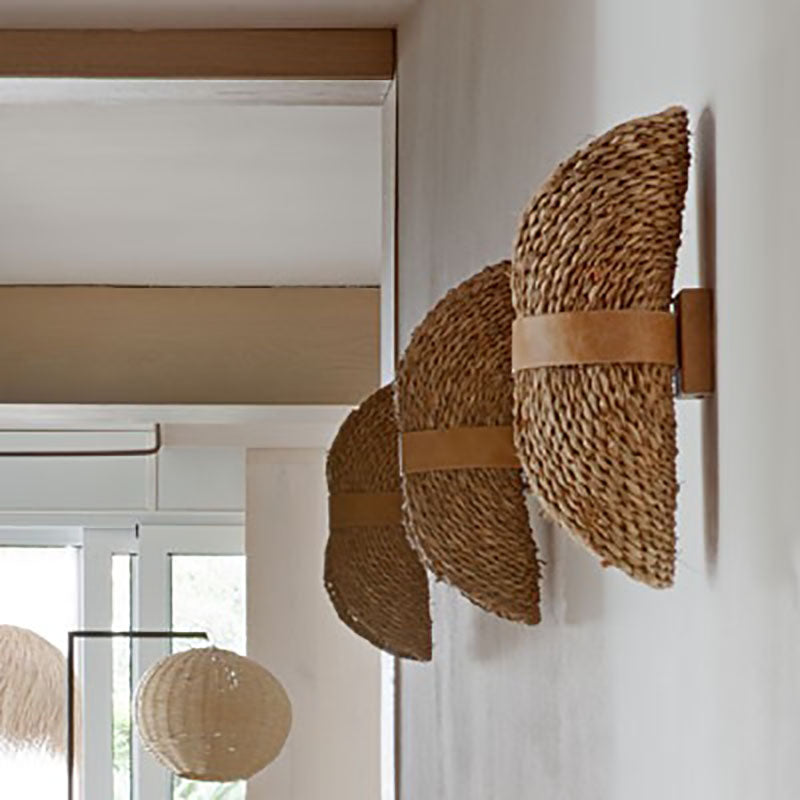 Side view of the Boho Chic Handwoven Rattan Wall Lamp showcasing its intricate design and warm glow.