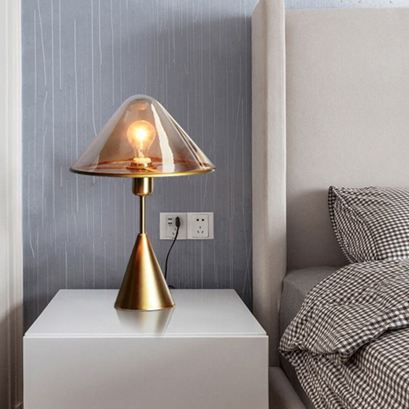 Elegant gold wrought iron table lamp showcasing its clear glass shade from a side angle.