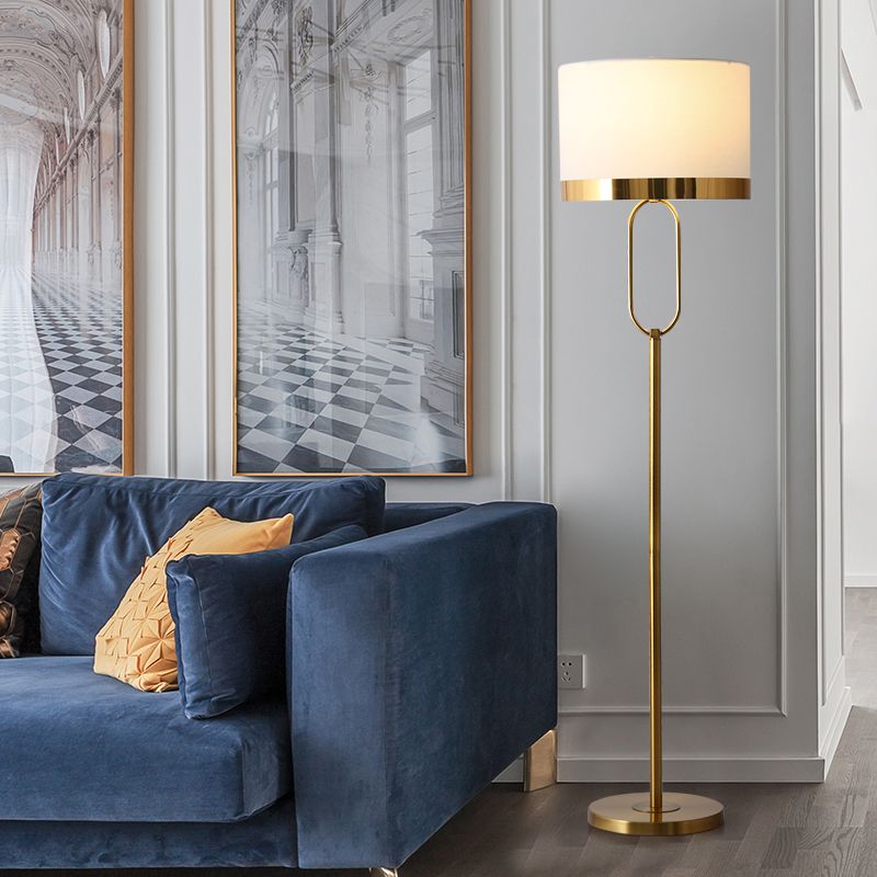 Elegant white column lamp with a drum shade illuminating a stylish living room.