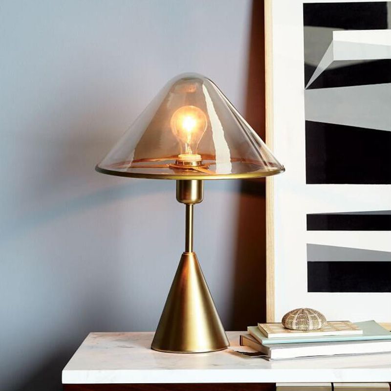 Elegant gold wrought iron table lamp showcasing its clear glass shade from a side angle.