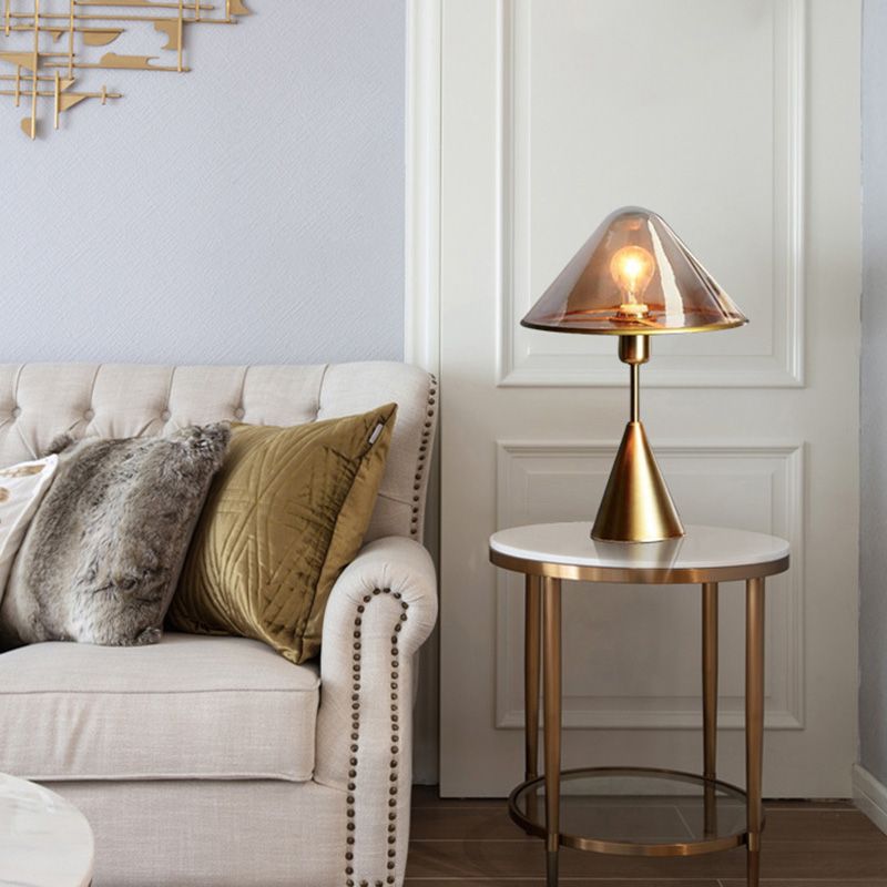 Unique gold table lamp placed on a bedside table, illuminating a warm, inviting ambiance.