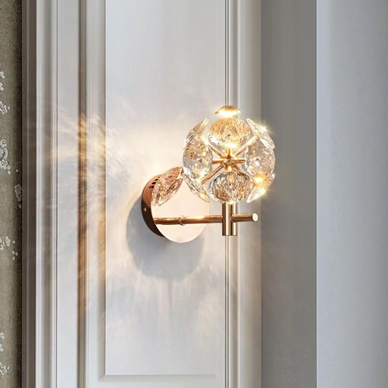 Close-up of the modern gold wall lamp featuring a clear crystal shade.