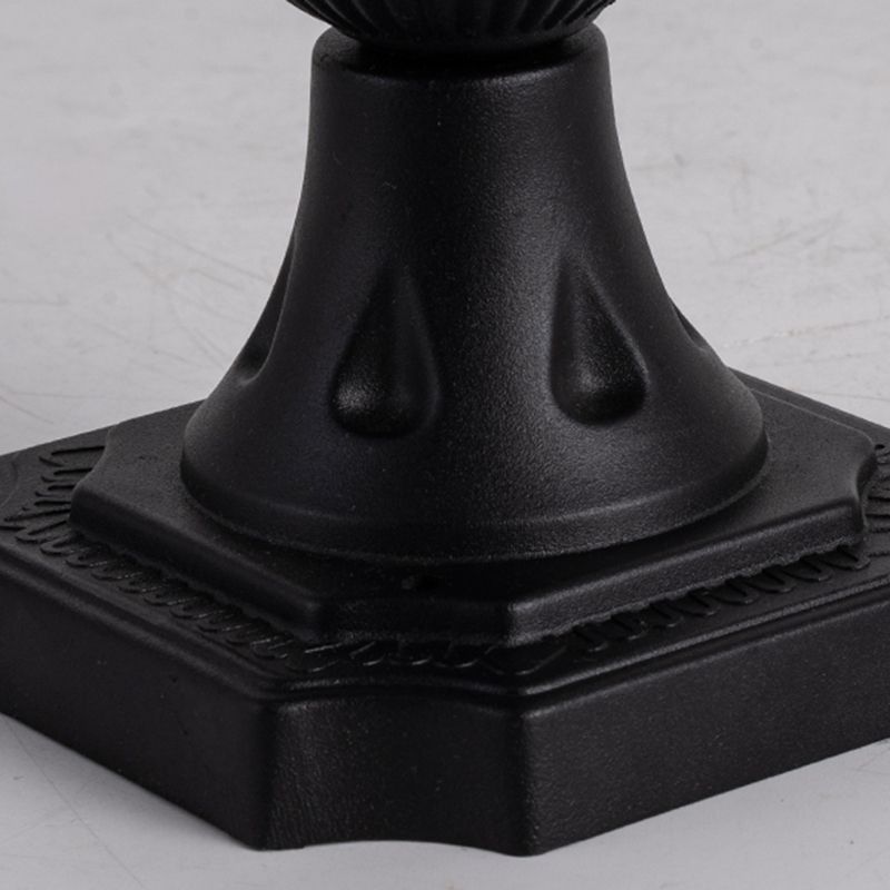 Black solar LED post light illuminating a courtyard at night.