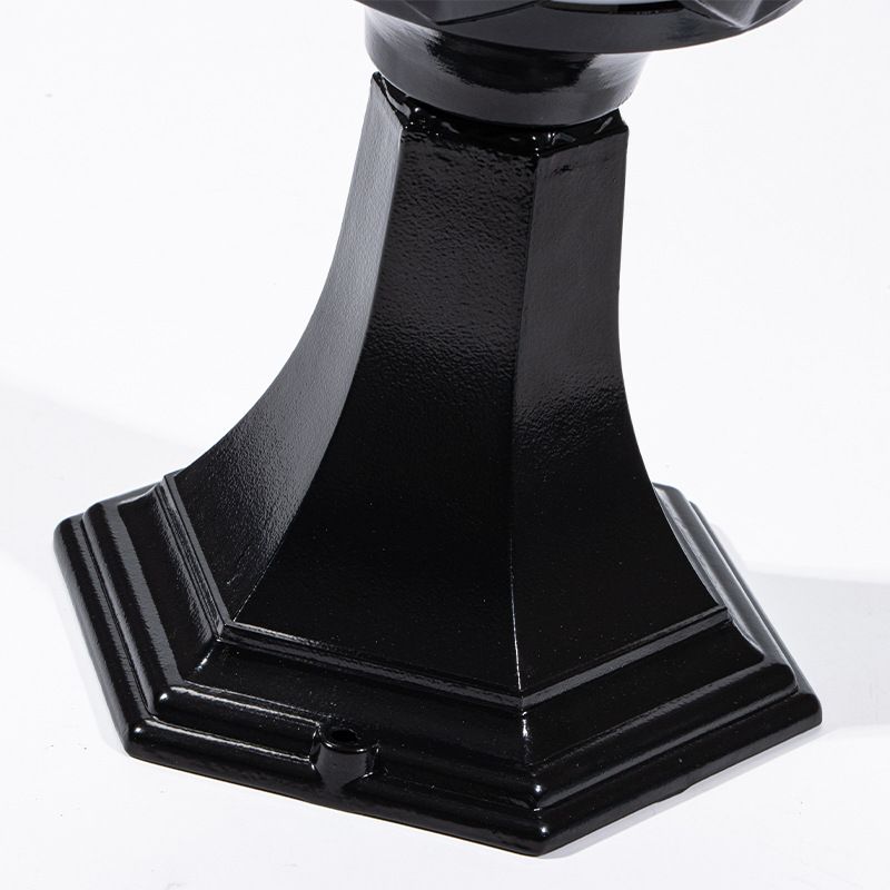 Black metal solar post light illuminating a garden pathway at night.