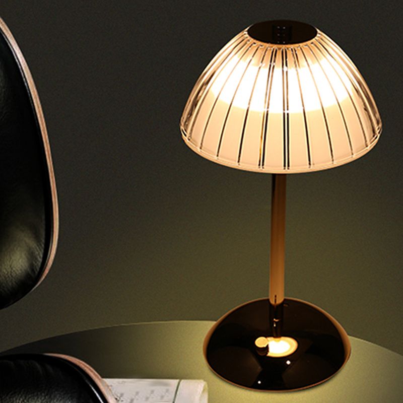 Elegant gold cordless table lamp with glass shade in a cozy living room setting.