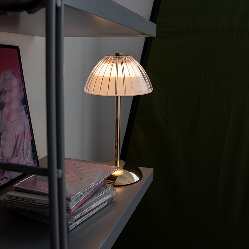 Elegant gold cordless table lamp with glass shade in a cozy living room setting.