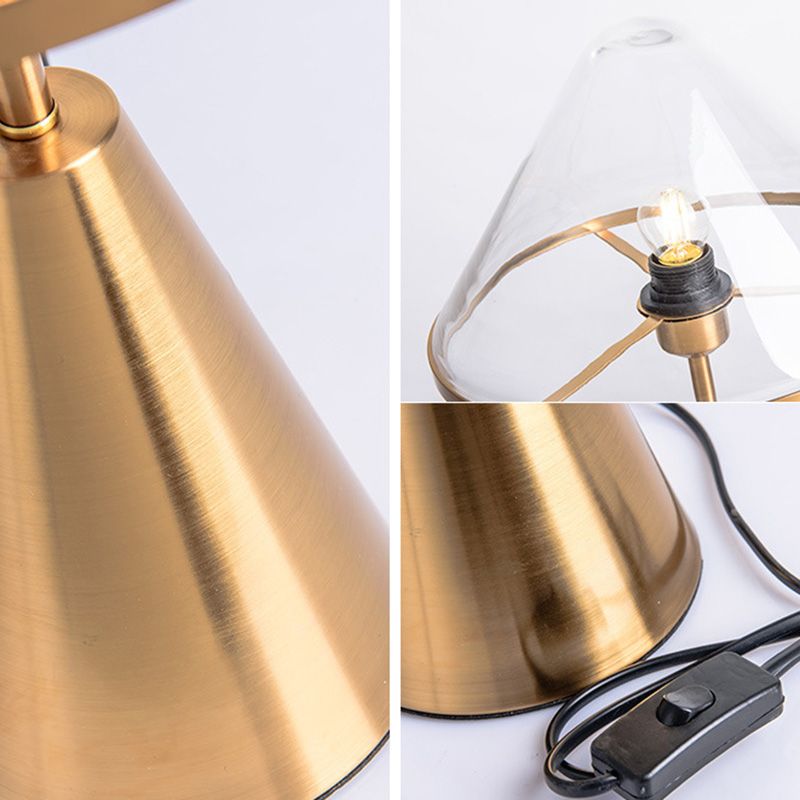 Elegant gold wrought iron table lamp showcasing its clear glass shade from a side angle.