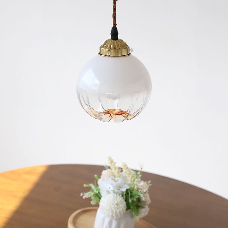 Adjustable brass pendant light showcasing its elegant white glass shade from a side angle.