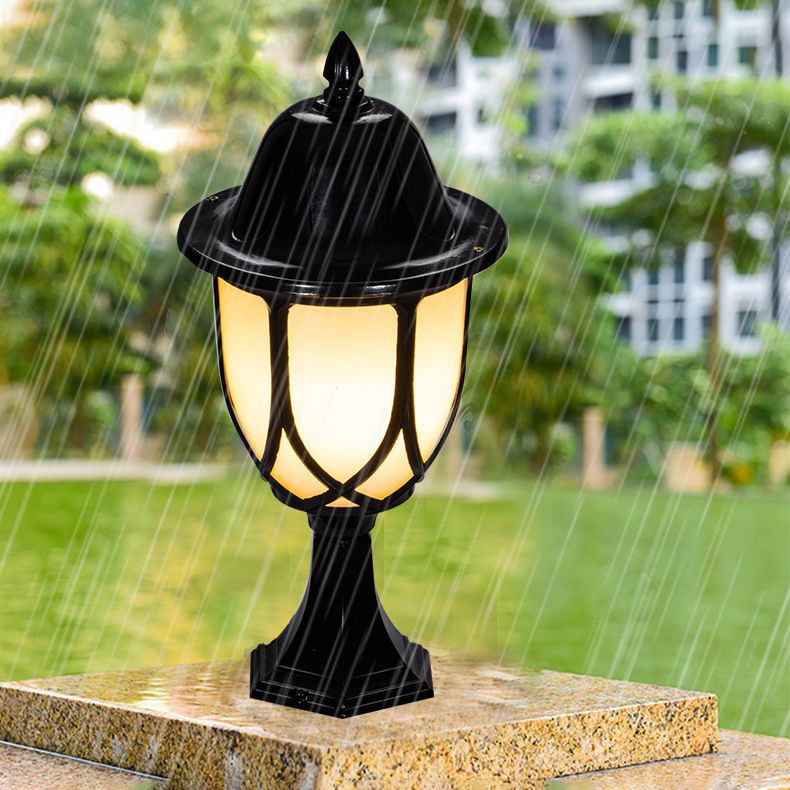 Black metal solar post light illuminating a garden pathway at night.