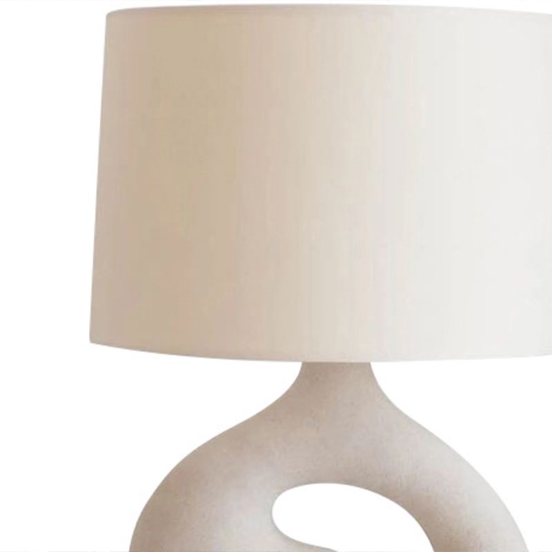 Stylish white lamp illuminating a cozy bedroom setting.