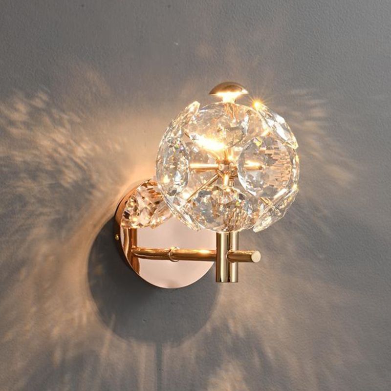 Close-up of the modern gold wall lamp featuring a clear crystal shade.