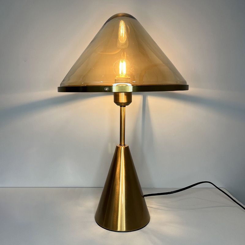 Elegant gold wrought iron table lamp showcasing its clear glass shade from a side angle.