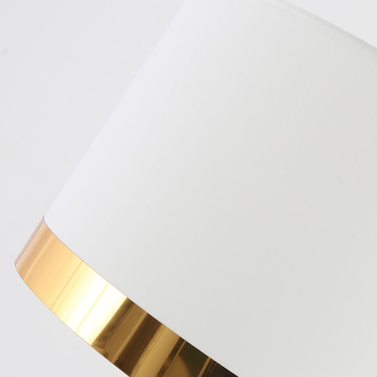 Elegant white column lamp with a drum shade illuminating a stylish living room.
