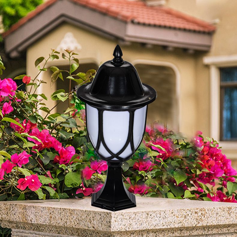 Black metal solar post light illuminating a garden pathway at night.