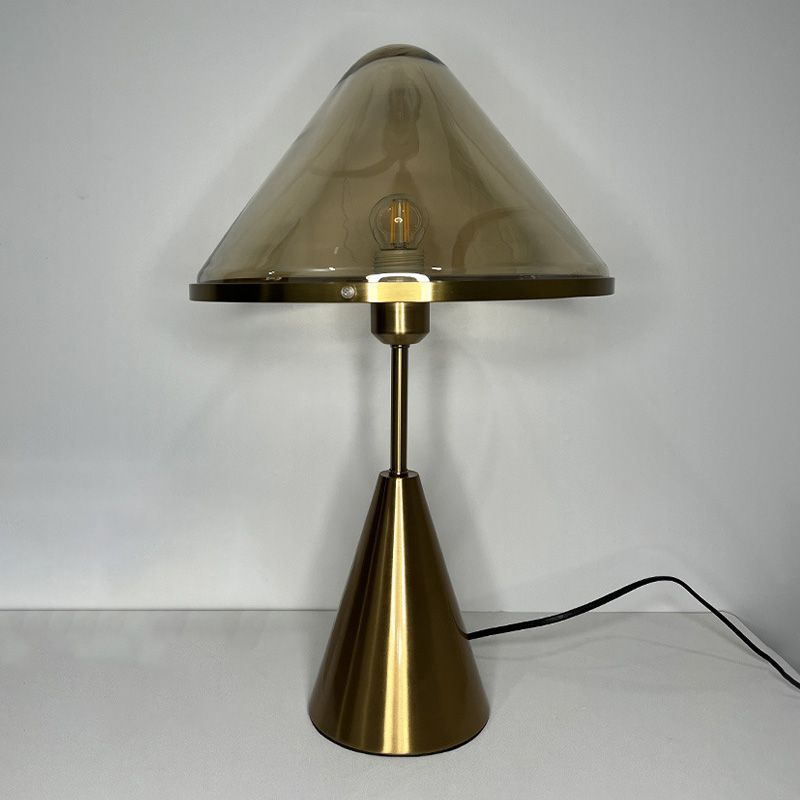 Unique gold table lamp placed on a bedside table, illuminating a warm, inviting ambiance.