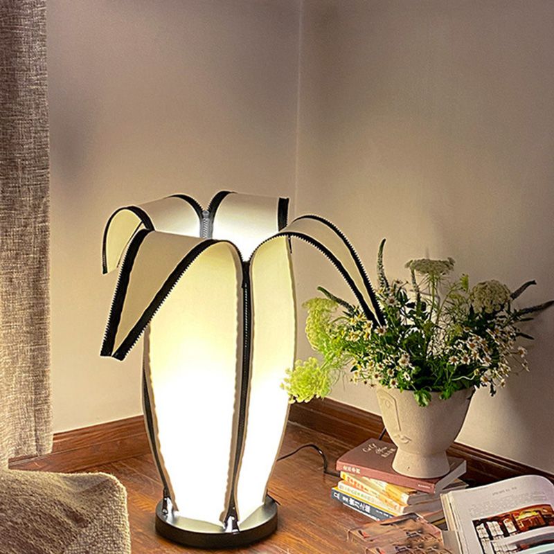Front view of charming banana-shaped modern table lamp on a bedside table.
