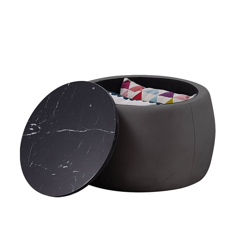 View of the black round storage ottoman coffee table in a cozy living room setting, highlighting storage capability.