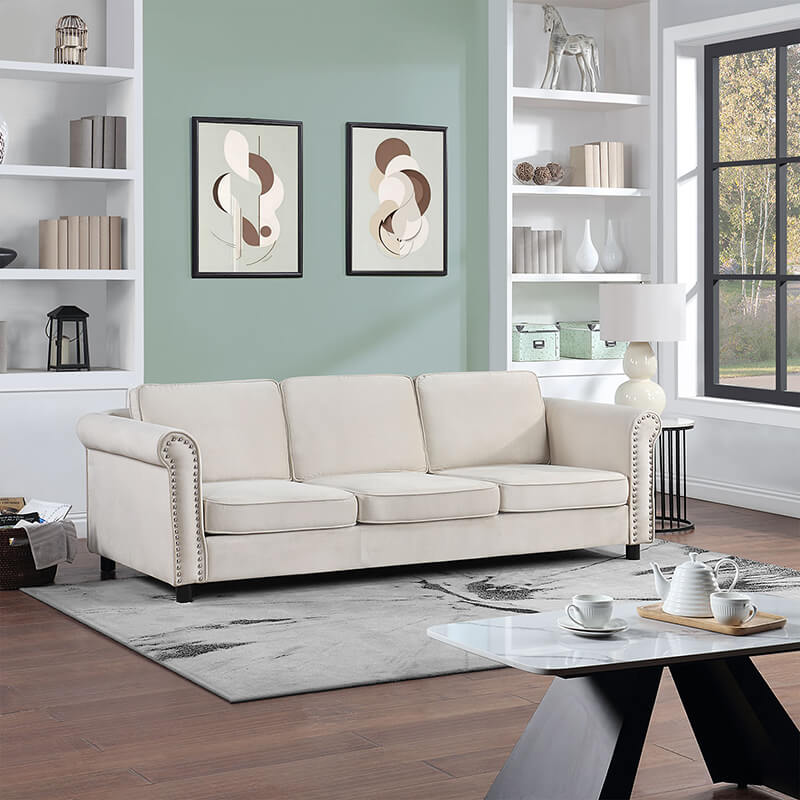 Beige mid-century velvet 3-seater sofa with round arms and nailhead trim in modern living room setting.
