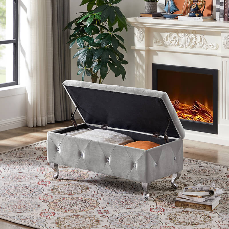Side view of the grey velvet storage ottoman bench in a stylish living room setting.