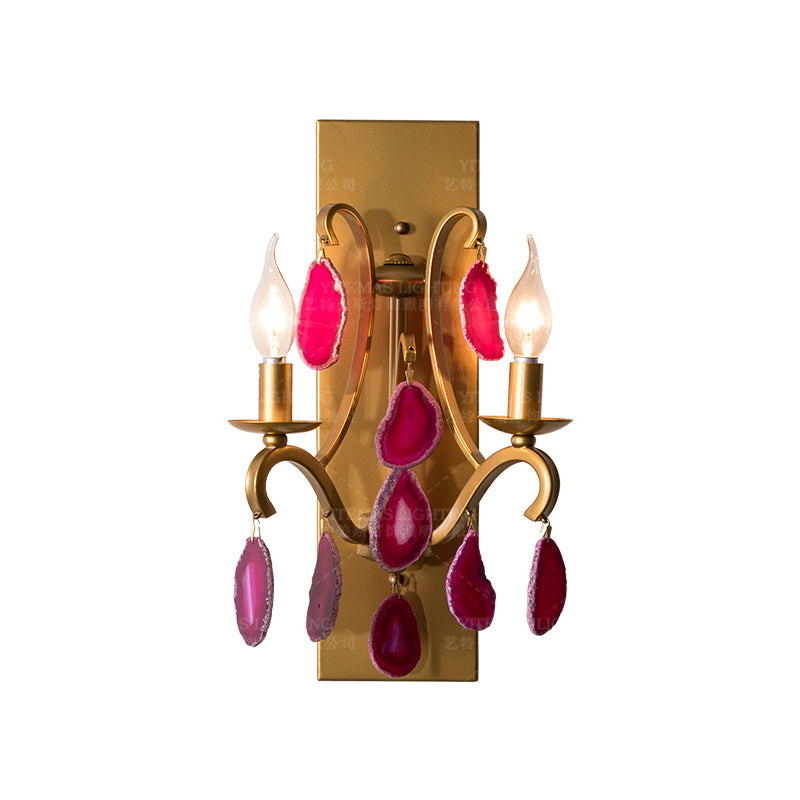 Elegant pink agate wall lamp with gold base, displayed in a cozy living room setting.