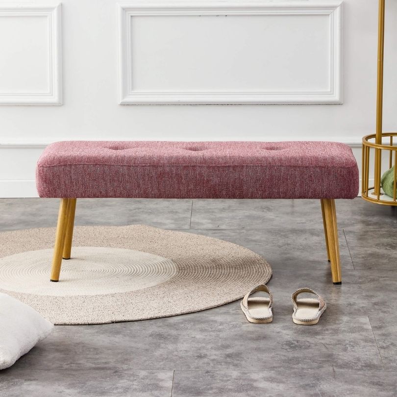 Front view of the pink linen bench in an entryway setting, showcasing its elegant design and metal legs.