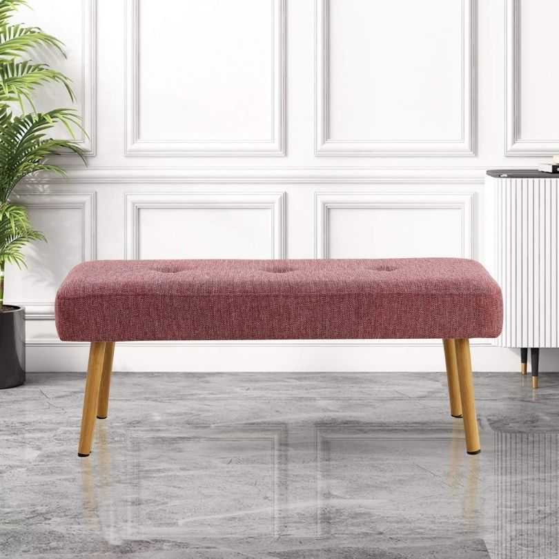 Front view of the pink linen bench in an entryway setting, showcasing its elegant design and metal legs.