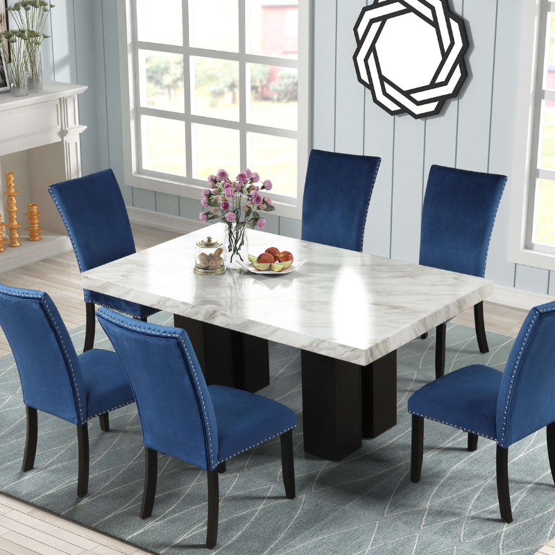 Luxury faux marble dining table set with blue velvet chairs from an angled view.