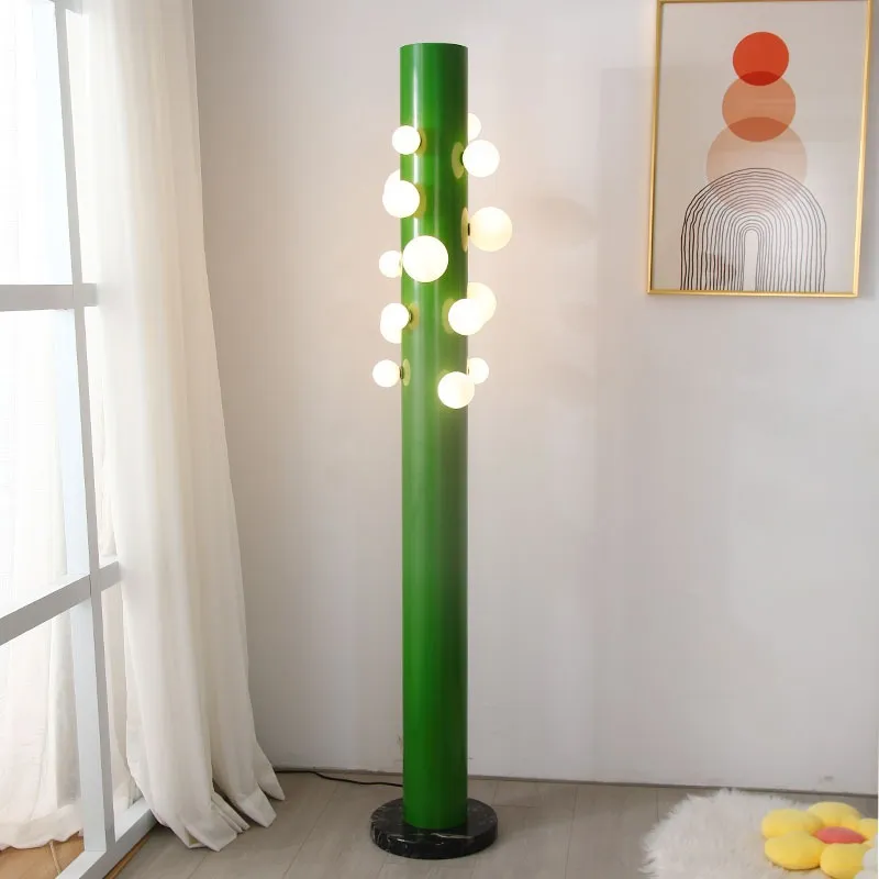 Elegant green cylinder glass floor lamp showcasing its intricate design and opal glass diffusers.