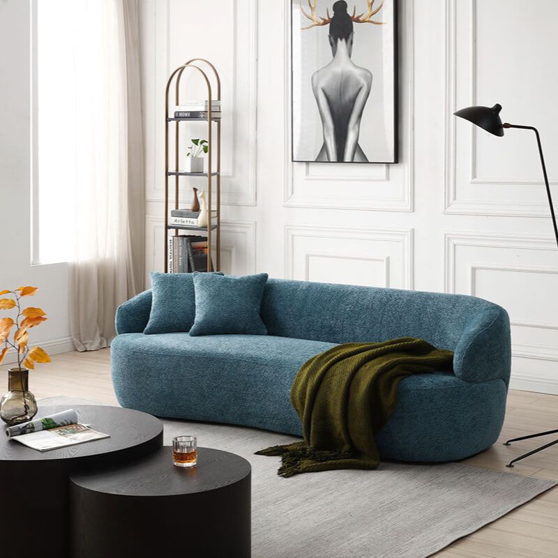 View of the elegant light blue mid-century curved sofa featuring plush throw pillows, perfect for a stylish living room setup.