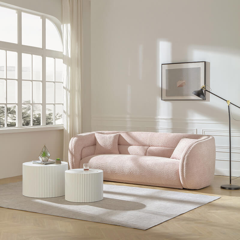 Curved pink velvet sofa in a chic living room setting, adorned with decorative pillows.
